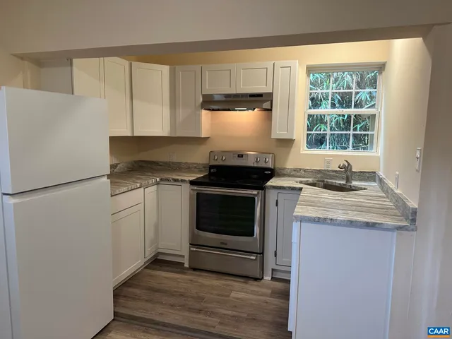 a kitchen with granite countertop white cabinets and white appliances