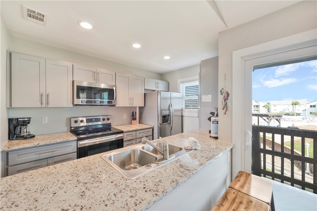 230 Cut-Off Road, Unit 204 Port Aransas, TX 78373 - Photo 12 of 37 a kitchen with stainless steel appliances granite countertop a refrigerator and a sink