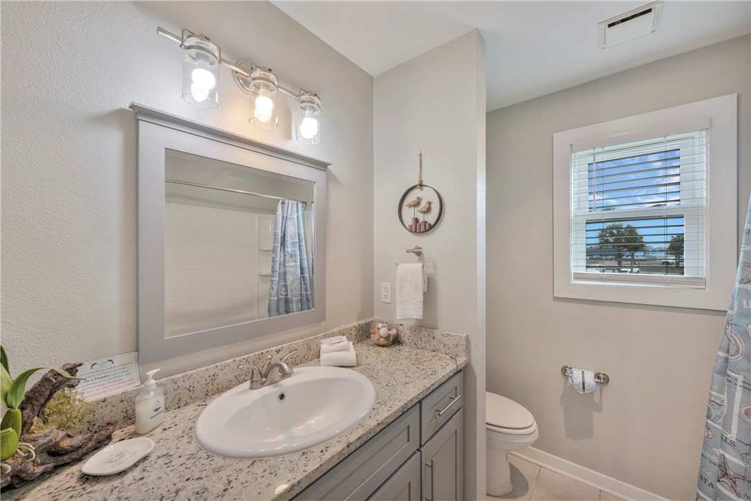 230 Cut-Off Road, Unit 204 Port Aransas, TX 78373 - Photo 18 of 37 a bathroom with a granite countertop sink toilet and a mirror