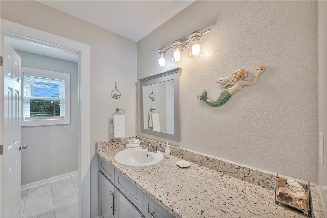 230 Cut-Off Road, Unit 204 Port Aransas, TX 78373 - Photo 23 of 37 a bathroom with a granite countertop sink a light fixture and a mirror