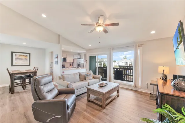 a living room with furniture kitchen view and a wooden floor
