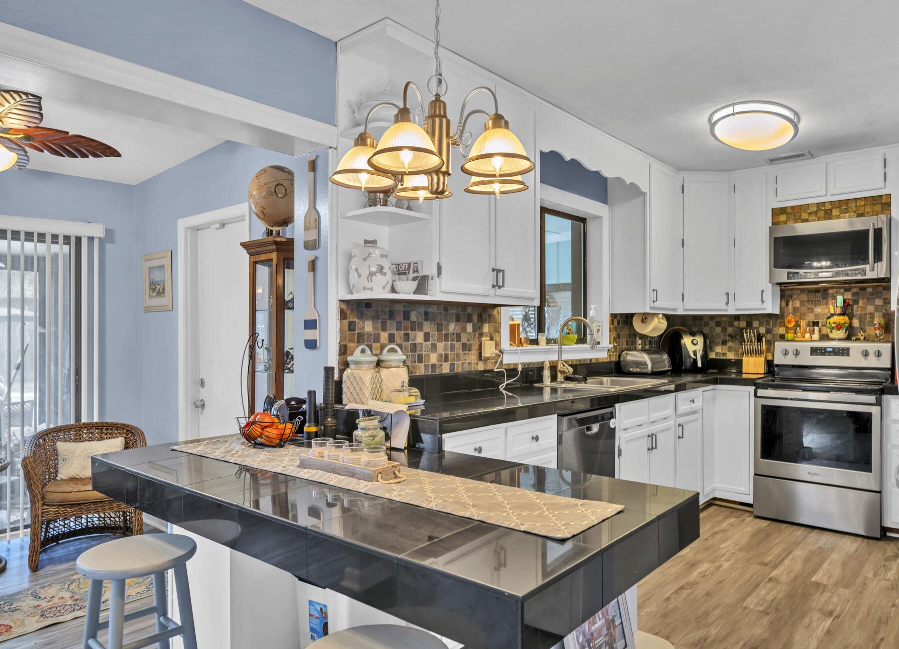 43 Ferry Road Northeast Fort Walton Beach, FL 32548 - Photo 4 of 23 a kitchen with stainless steel appliances granite countertop a stove a sink dishwasher a dining table and chairs with wooden floor