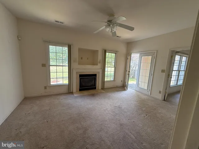 an empty room with windows fireplace and fan