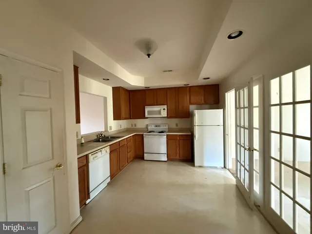 a large kitchen with stainless steel appliances granite countertop a large counter top and a refrigerator