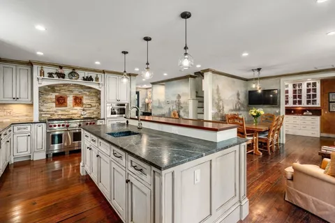 a kitchen with stainless steel appliances granite countertop a sink a stove and a wooden floors