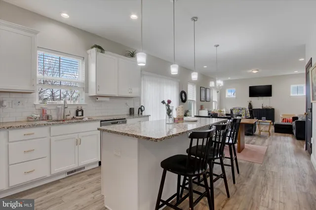 a kitchen with cabinets a sink dishwasher a dining table and chairs with wooden floor