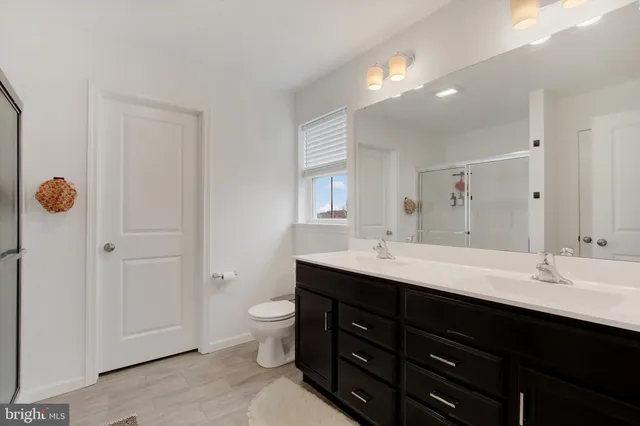 a bathroom with a double vanity sink a toilet and a mirror