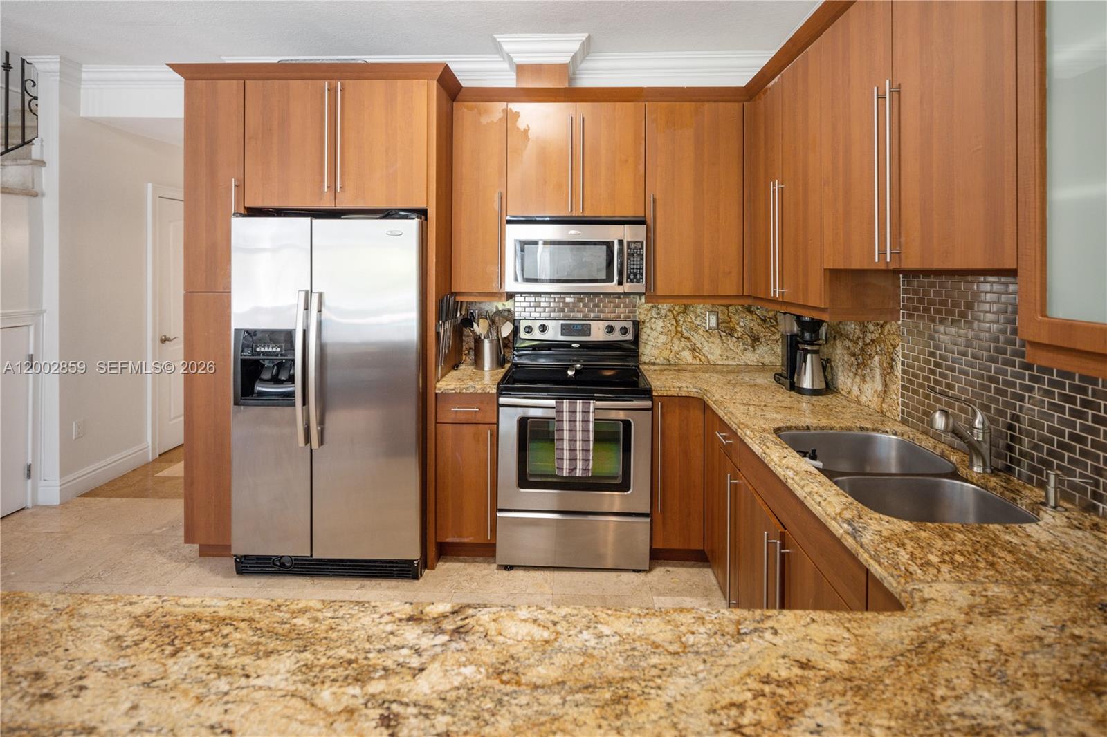 3171 Indiana Street, Unit 3171 Miami, FL 33133 - Photo 6 of 14 a kitchen with stainless steel appliances granite countertop a refrigerator a stove and a sink with wooden cabinets