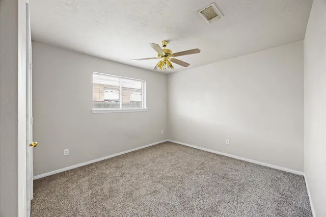 an empty room with a window and a fan