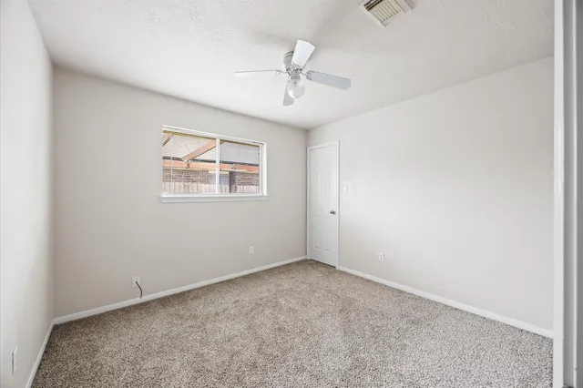 an empty room with windows and ceiling fan