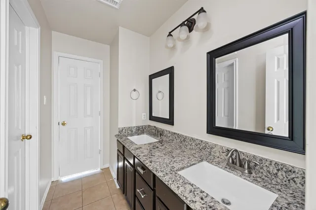 a bathroom with a granite countertop double vanity sink and a mirror