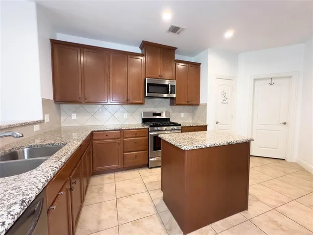 a kitchen with stainless steel appliances granite countertop a stove a sink and a microwave