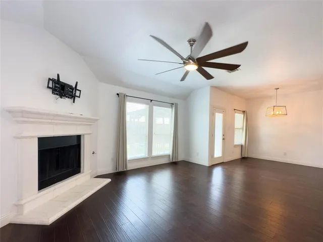a view of an empty room with wooden floor and a fireplace