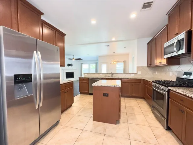 a kitchen with stainless steel appliances granite countertop a refrigerator a sink a stove top oven and cabinets