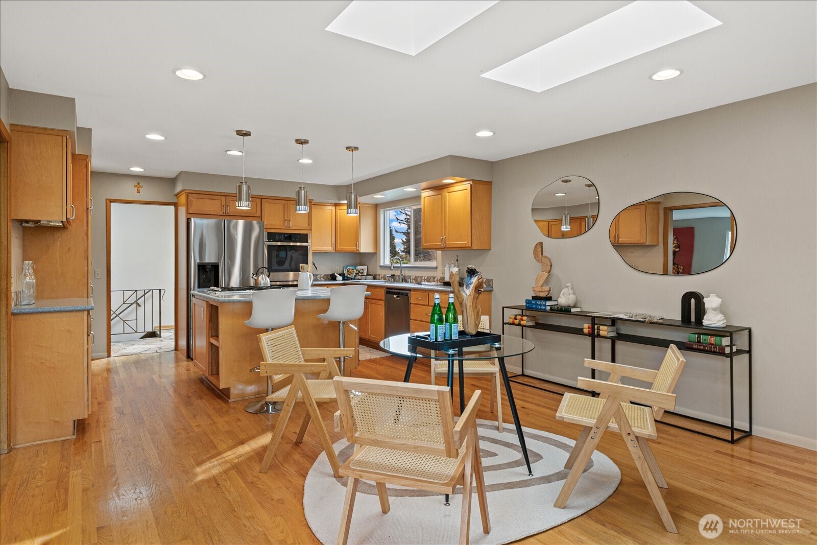 6520 Northeast 60th Street Seattle, WA 98115 - Photo 14 of 40 a kitchen with stainless steel appliances kitchen island granite countertop a refrigerator a stove a sink a dining table and chairs with wooden floor