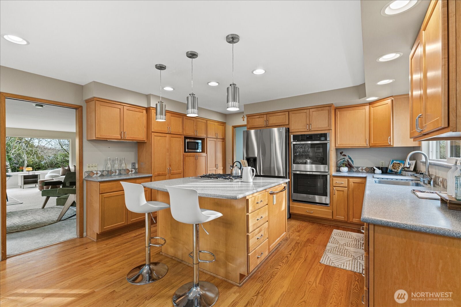 6520 Northeast 60th Street Seattle, WA 98115 - Photo 17 of 40 a kitchen with stainless steel appliances granite countertop a stove top oven a sink dishwasher a dining table and chairs with wooden floor