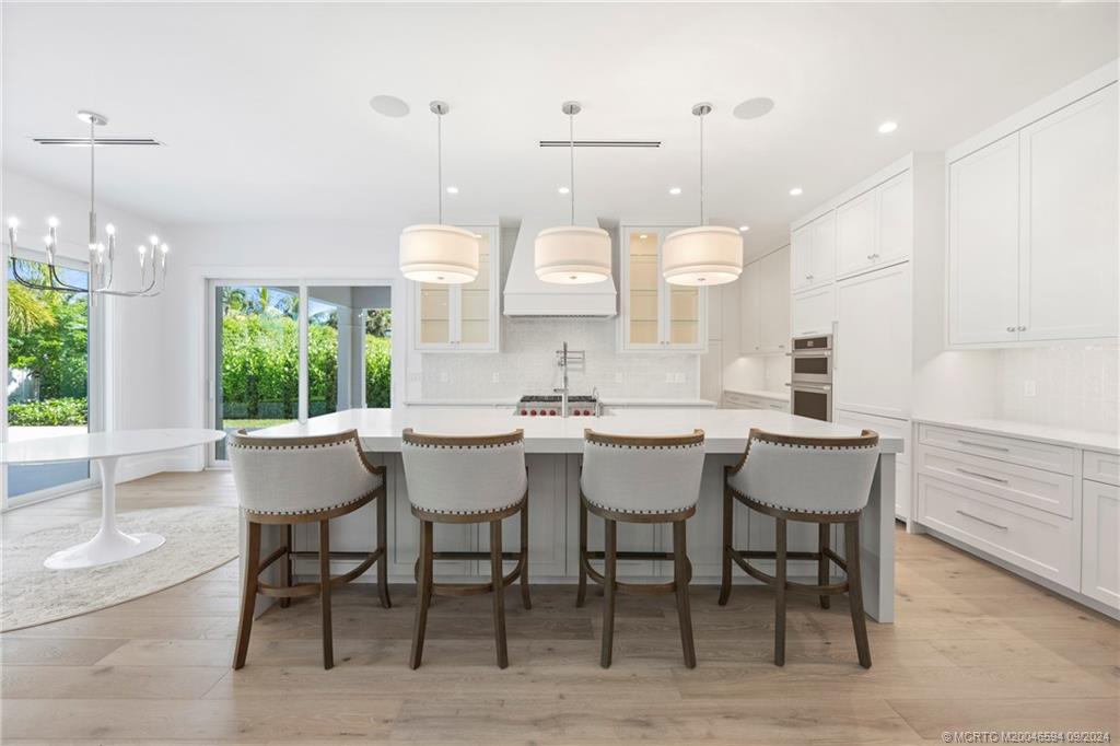 180 Beacon Lane Jupiter, FL 33469 - Photo 15 of 63 a kitchen with kitchen island a dining table chairs and white cabinets