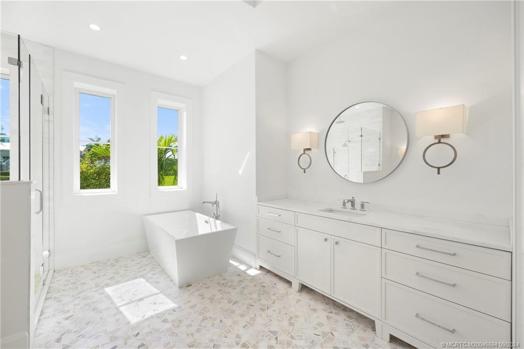 180 Beacon Lane Jupiter, FL 33469 - Photo 22 of 63 a bathroom with a double vanity sink a mirror and a bathtub
