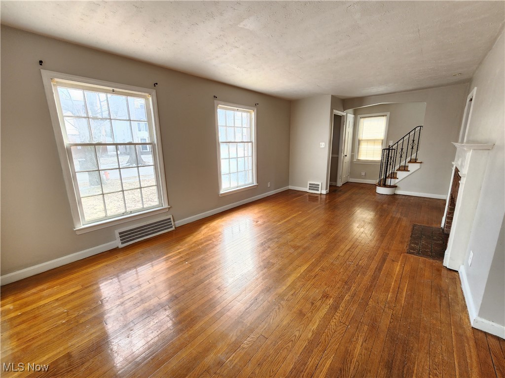 1160 Brentwood Road Cleveland, OH 44121 - Photo 7 of 26 Unfurnished living room featuring hardwood flooring, a fireplace, and a textured ceiling