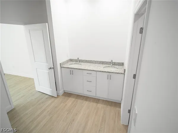 a view of a kitchen with white cabinets and wooden floor