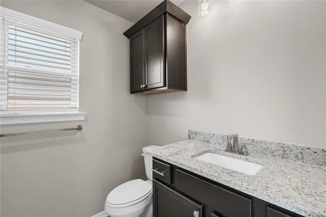 a bathroom with a granite countertop toilet sink and mirror