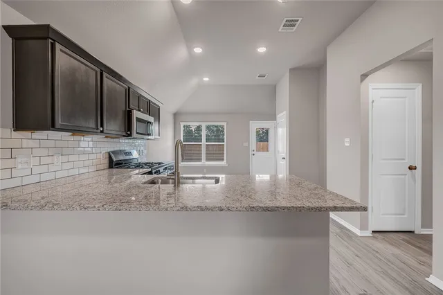 a kitchen with kitchen island granite countertop a sink window and cabinets