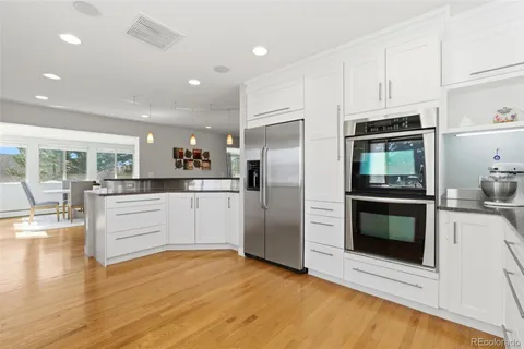 a large white kitchen with stainless steel appliances granite countertop a stove and a sink