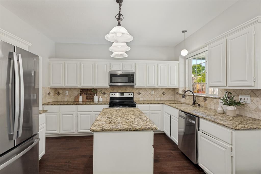 1228 Concho Drive Benbrook, TX 76126 - Photo 15 of 39 Modern kitchen featuring white cabinetry, granite countertops, stainless steel appliances, a tiled backsplash, and wood-finish flooring