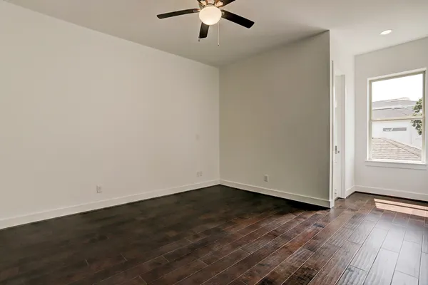 an empty room with wooden floor chandelier fan and windows