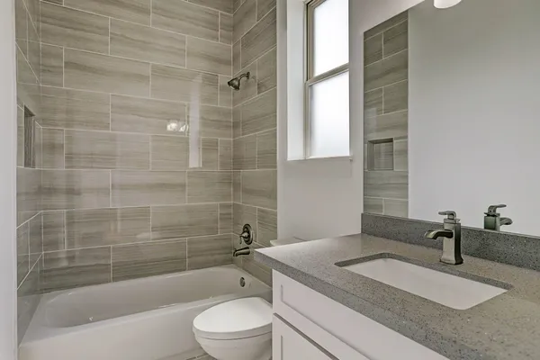 a bathroom with a granite countertop sink a toilet a mirror and bathtub