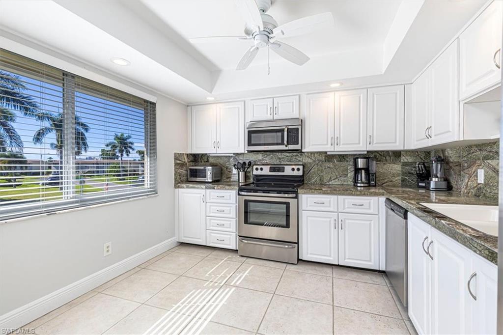 230 Albi Road, Unit 2494 Naples, FL 34112 - Photo 5 of 22 Kitchen featuring appliances with stainless steel finishes, white cabinets, a tray ceiling, light tile patterned floors, and ceiling fan