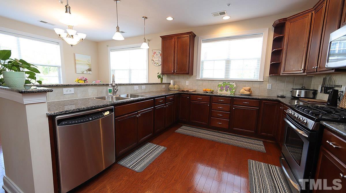 10411 Rosegate Court, Unit 202 Raleigh, NC 27617 - Photo 13 of 35 a kitchen with stainless steel appliances granite countertop wooden cabinets a sink dishwasher a stove and a refrigerator with wooden floor