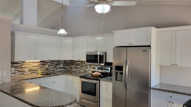 a kitchen with granite countertop a refrigerator stove and sink