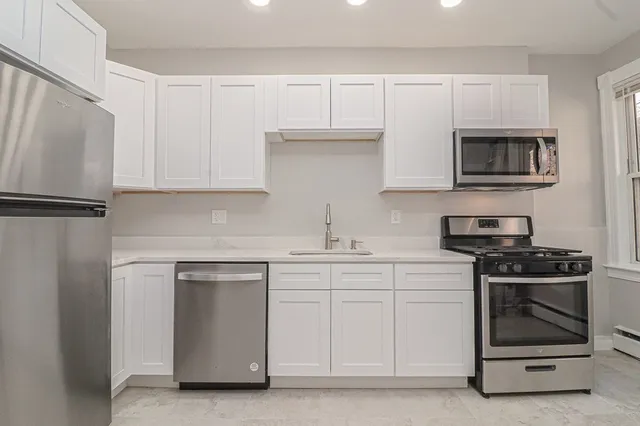 a kitchen with white cabinets and stainless steel appliances