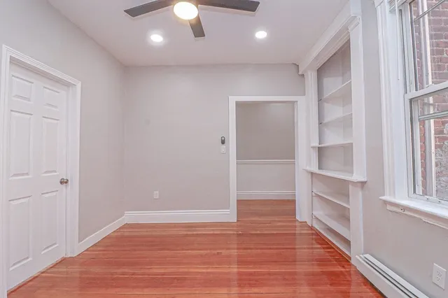 a view of an empty room with a window and wooden floor
