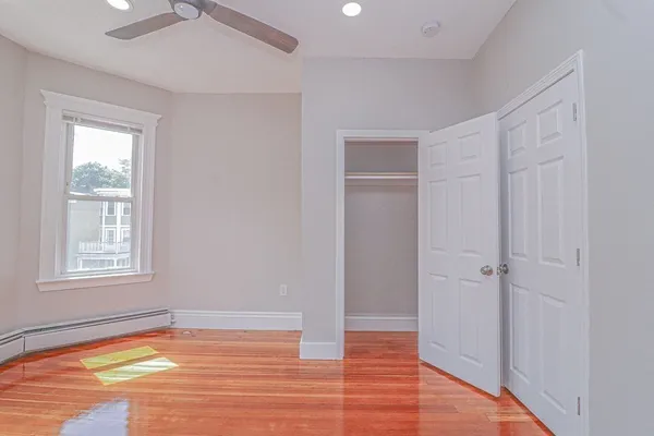 a view of an empty room with window and wooden floor