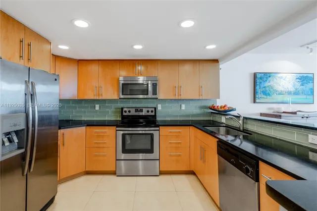a kitchen with stainless steel appliances granite countertop a sink a stove and a refrigerator
