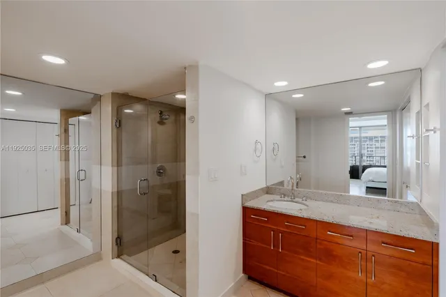 a bathroom with a granite countertop sink mirror and shower