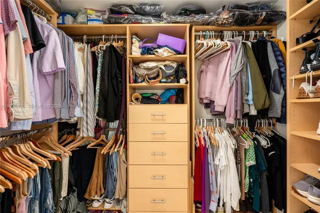 a view of walk in closet with clothes and shoes