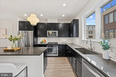 a kitchen with kitchen island granite countertop a sink stainless steel appliances and cabinets