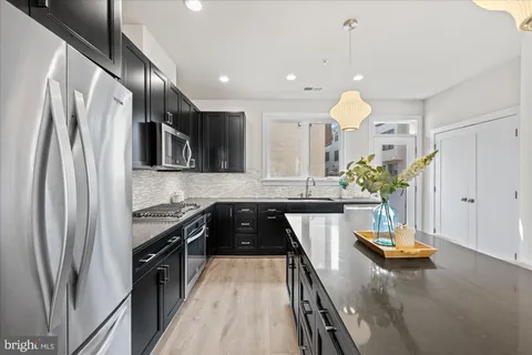 a kitchen with kitchen island granite countertop a sink a counter top space appliances and cabinets