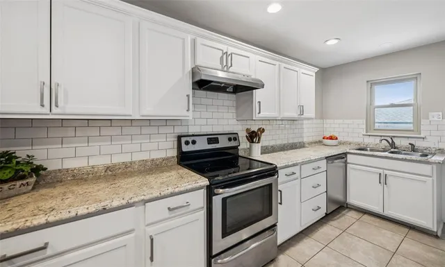 a kitchen with granite countertop white cabinets white appliances and a sink