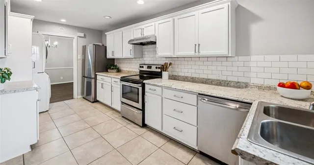 a kitchen with granite countertop a sink stove and cabinets