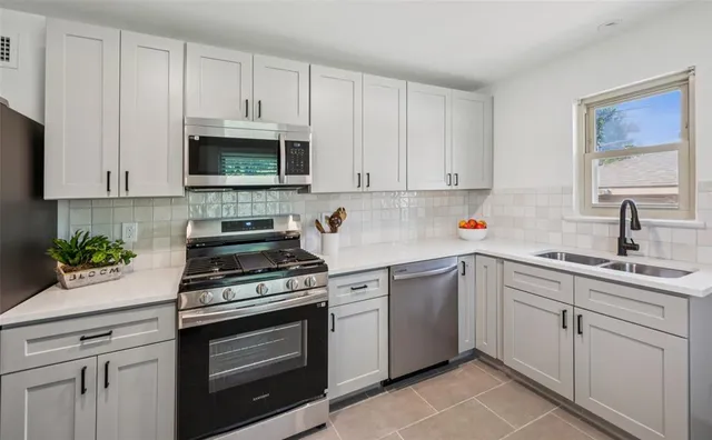 a kitchen with white cabinets and appliances
