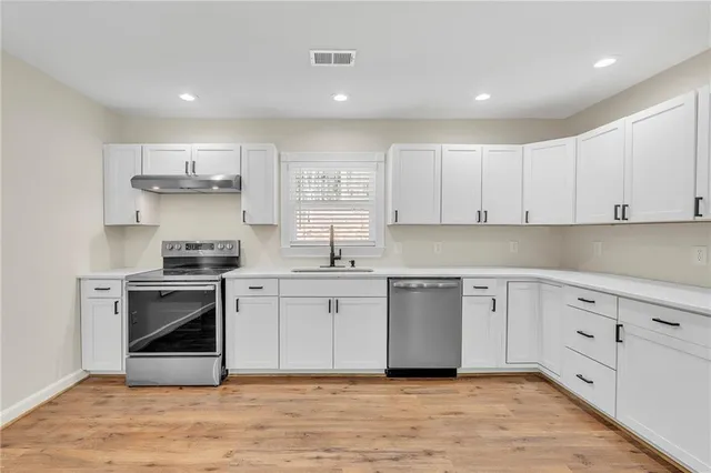 a kitchen with stainless steel appliances granite countertop a stove a sink and a refrigerator with wooden floors