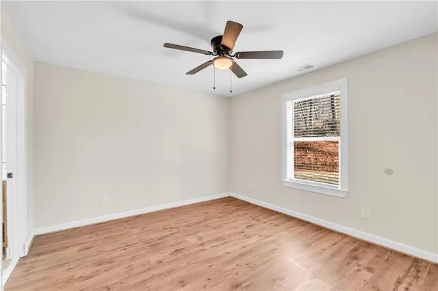 an empty room with wooden floor a ceiling fan and closet