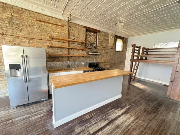 a view of kitchen with stainless steel appliances wooden floor and chair