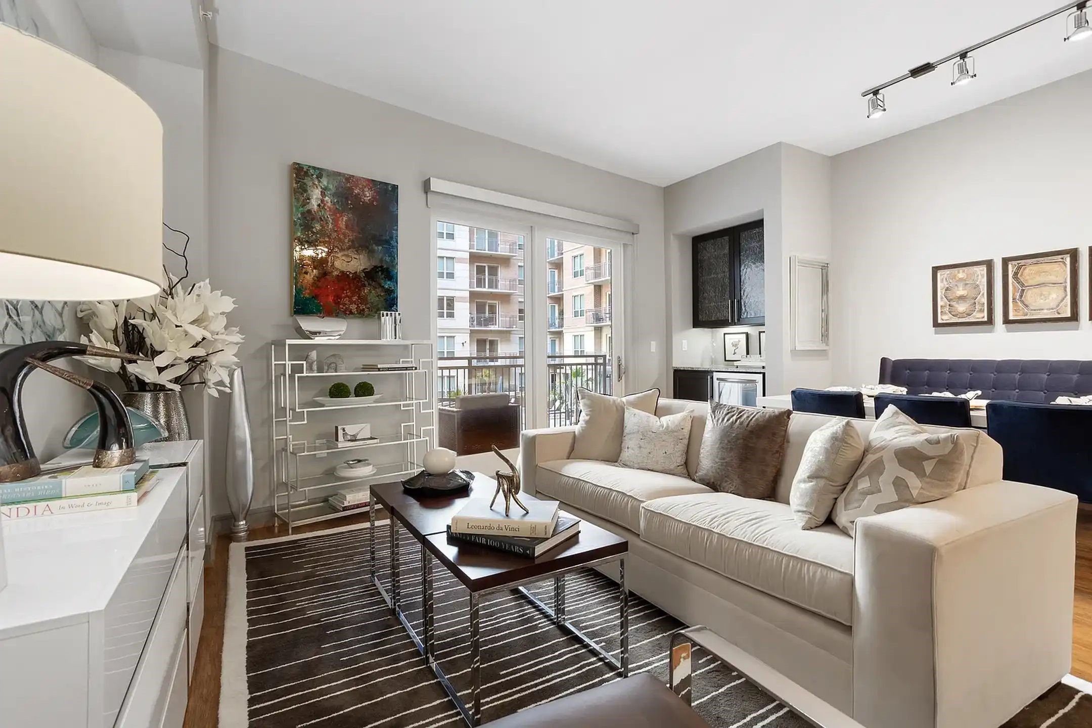 2724 Kipling Street, Unit 504 Houston, TX 77098 - Photo 25 of 30 This transitional living space effortlessly shifts from a peaceful retreat to a premier social hub. Start your evening by hosting a formal dinner at the navy tufted banquette, and unwind on the plush cream sofa—all while floor-to-ceiling glass doors extend your experience onto a private balcony. This is curated, high-end living designed for both quiet nights and sophisticated entertaining.