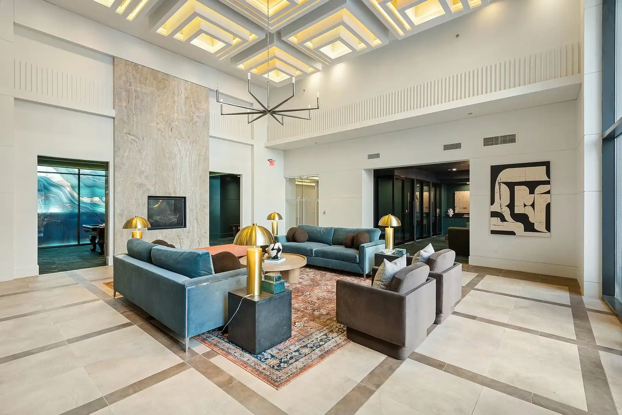 2724 Kipling Street, Unit 504 Houston, TX 77098 - Photo 6 of 30 This expansive resident lounge is a masterclass in architectural geometry and "maximalist modern" design. The space is anchored by a staggering double-height ceiling featuring a coffered, tiered geometric installation with integrated golden cove lighting, creating a rhythmic, glowing canopy.