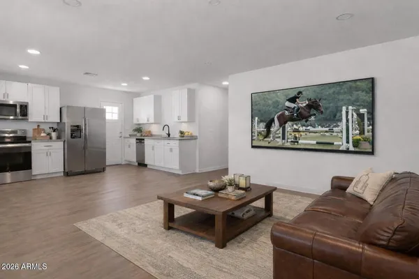 a living room with stainless steel appliances kitchen island granite countertop a couch and a view of kitchen sink